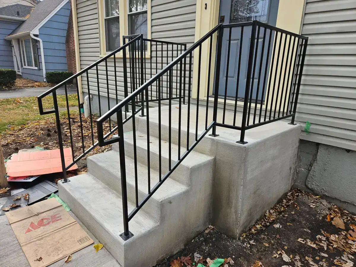 Custom black steel railing fabricated and installed on new concrete steps